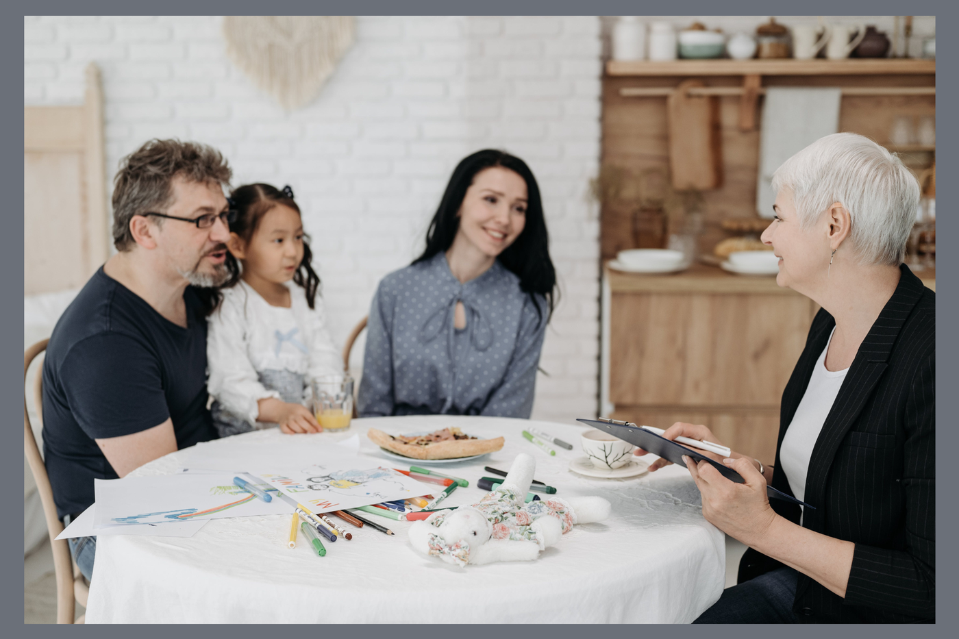 foster family, dhs caseworker, sitting at kitchen table with artwork and stuffed animal